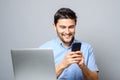 Joyful man using cellphone and sitting at the table with laptop Royalty Free Stock Photo