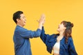 Joyful man and woman greeting each other with high five on yellow background Royalty Free Stock Photo