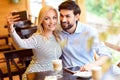Joyful man and woman using smartphone in cafeteria Royalty Free Stock Photo