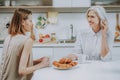 Happy young woman is having breakfast with mother at home