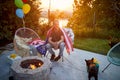 Joyful middle aged man with american flag around his back, sitting outdoors by a fireplace in his backyard, enjoying sunny summer