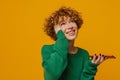 Joyful middle-aged woman holding smartphone isolated over yellow background