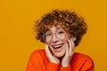 Joyful middle-aged woman touching her face isolated over yellow background