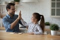 Joyful millennial father giving high five to small daughter.