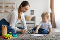 Joyful millennial mother and toddler son sitting on floor, drawing together using colorful pencils and sheets of paper Royalty Free Stock Photo