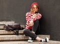 Smiling student girl using mobile phone while sitting outside with takeaway coffee before in morning Royalty Free Stock Photo