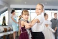 Little children practicing waltz dance in school-hall decorated with Christmas-tree