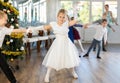 Little children practicing waltz dance in school-hall decorated with Christmas-tree