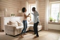 Joyful mixed race family spouse dancing in wooden living room. Royalty Free Stock Photo