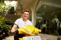 Transgender individual smiles atop yellow scooter outside coworking space, embracing urban eco commute. Joyful moment