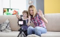 Joyful mother and daughter hold their hand in greeting to video camera screen Royalty Free Stock Photo