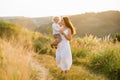 Joyful mother with her little son in her arms. Elegant woman with little boy walking in the field with beautiful landscape. Royalty Free Stock Photo