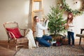 Joyful mother and lovely girl daughter in cozy knitted sweaters decorating Christmasmas fir tree with new year baubles and toys in