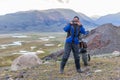 Joyful motorcyclist left the motorcycle aside and taking pictures of his friends in Mongolian Altai