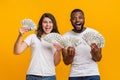Joyful multiracial couple holding lot of dollar banknotes, rejoicing success together