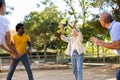 Joyful multiracial group of mature adult people playing volleyball game outdoors