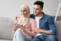 Joyful muslim couple watching photos on mobile phone together