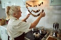 Nice senior woman checking dried mushrooms in kitchen Royalty Free Stock Photo