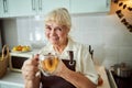 Joyful old woman in apron offering cup of herbal tea Royalty Free Stock Photo