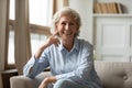 Happy mature granny sitting on couch smiling posing for camera