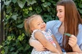 Joyful older sister holding younger sister, playing and laughing, having fun. Teen girl holding baby girl on summer day Royalty Free Stock Photo