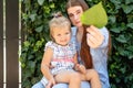 Joyful older sister holding younger sister, playing and laughing, having fun. Teen girl holding baby girl on summer day Royalty Free Stock Photo