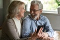 Joyful older spouses embrace relax with cell discuss funny video Royalty Free Stock Photo