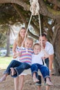 Joyful parents pushing their children on a swing Royalty Free Stock Photo