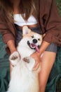 Joyful playtime, young woman cuddles with a smiling Pembroke Welsh Corgi in the park