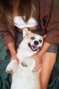 Joyful playtime, young woman cuddles with a smiling Pembroke Welsh Corgi in the park