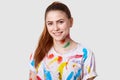 Joyful pleased European female artist has pony tail, toothy smile, shows white even teeth, dressed in casual t shirt, being dirty Royalty Free Stock Photo