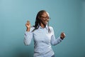 Joyful pleased young woman enjoying dancing and vibing while listening to music playlist on blue background. Royalty Free Stock Photo