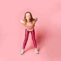 Joyful preschool girl in a stylish blouse and leggings is teasing someone by leaning forward, grimacing and wallowing. Full length Royalty Free Stock Photo