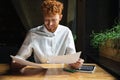 Joyful readhead young man in white shirt working with papers at Royalty Free Stock Photo