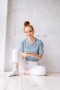 Joyful redhead young woman wearing wireless earphones listening relaxed music using cell phone. Royalty Free Stock Photo