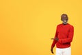 Joyful senior Black man in a red sweater laughing and presenting something to his side Royalty Free Stock Photo