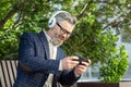 Joyful senior businessman enjoying music on headphones outdoors in a suit Royalty Free Stock Photo
