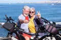 A joyful senior couple enjoying sea excursion with their bicycles, horizon on the sea. Active beautiful retirees enjoying healthy Royalty Free Stock Photo