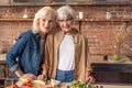 Joyful senior ladies cooking with enjoyment