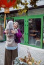 Joyful senior lady in warm jacket hugs long haired best friend meeting on city street