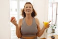 Joyful senior woman holding an apple and glass of orange juice, Royalty Free Stock Photo