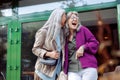 Joyful senior women friends with natural grey hair have fun on city street Royalty Free Stock Photo