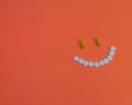 Joyful smile made of pills on an orange background