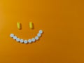 Joyful smile made of pills on an orange background