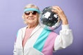 Joyful smiling aged woman portrait dressed in sportswear, holding mirrow ball.