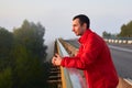 Joyful smiling brunette man on a bridge on a foggy morning