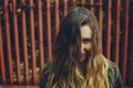 Joyful smiling girl with her beautiful long hair tousled and covering her face on a sunny windy day. Red fence on a background. Royalty Free Stock Photo