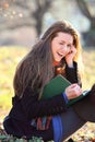 Joyful and smiling girl reading a book in the park