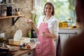 Joyful smiling housewife standing in kitchen, finished making a salad, looking at someone and talking