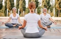 Senior couple staying in lotus pose in front of female yoga trainer during yoga class in city park Royalty Free Stock Photo